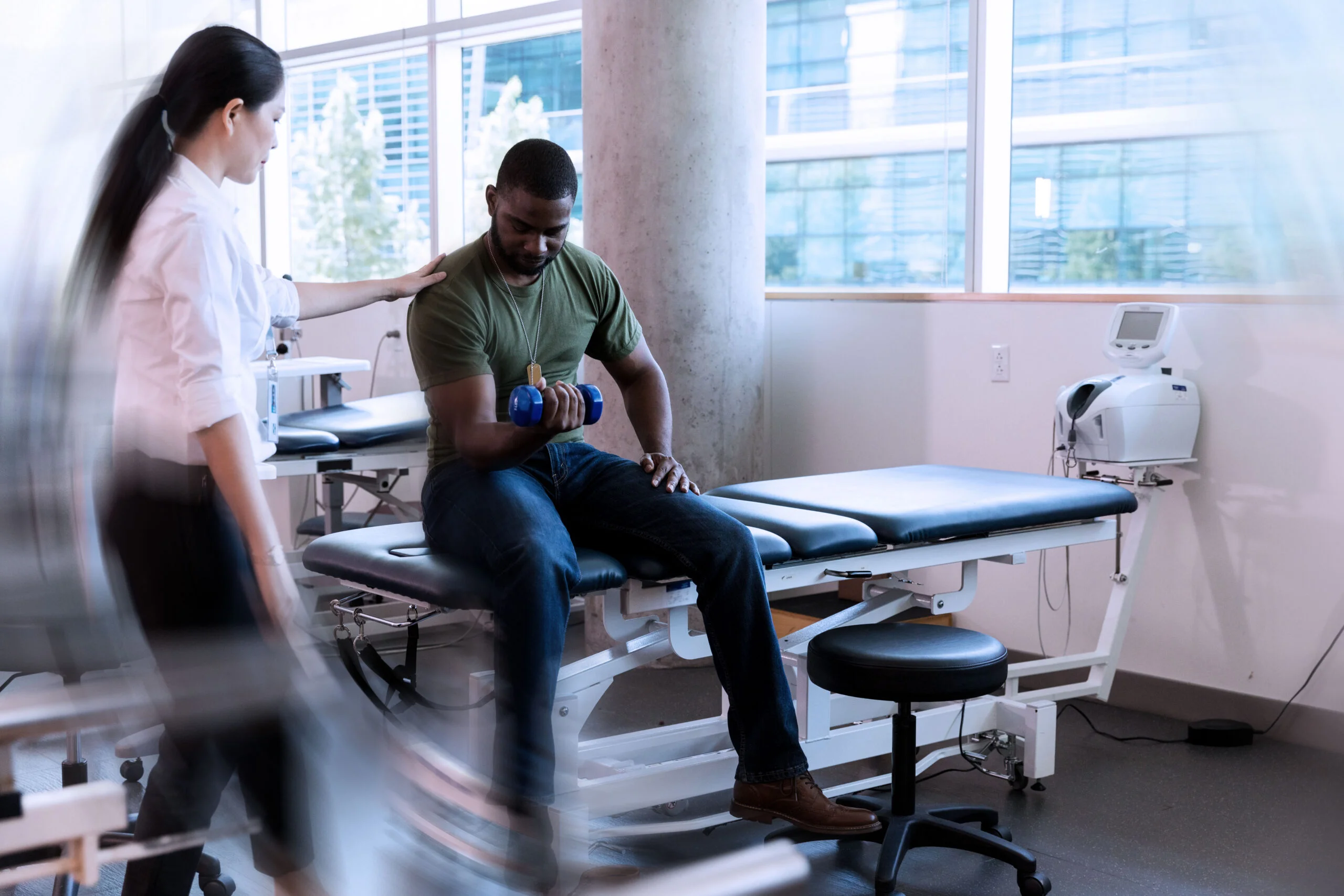 Therapist stands back to check form for veteran patient using weight