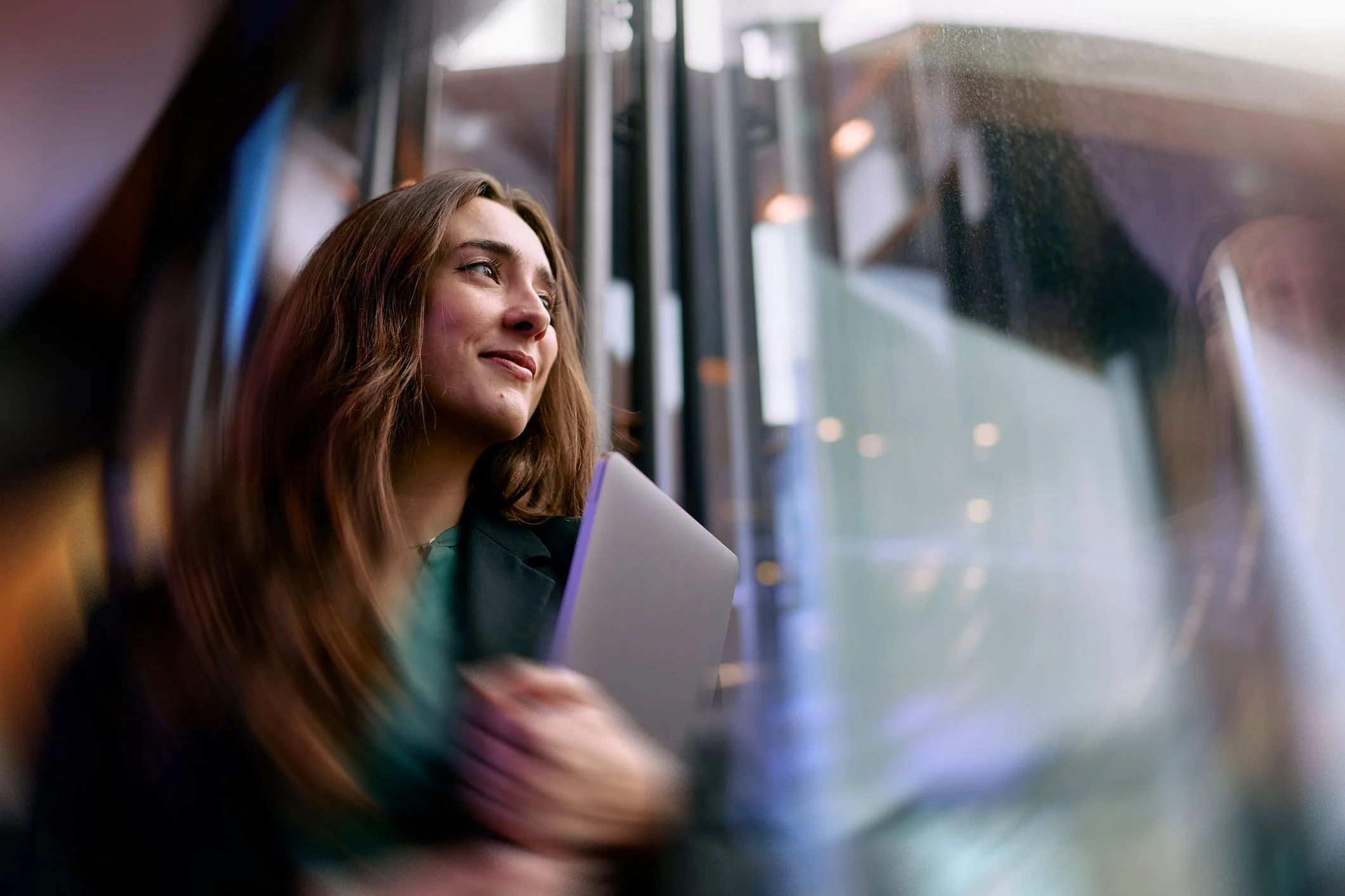 Businesswoman with laptop looking hopeful in modern office building